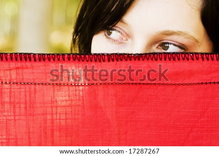 Young curious woman spying behind veil