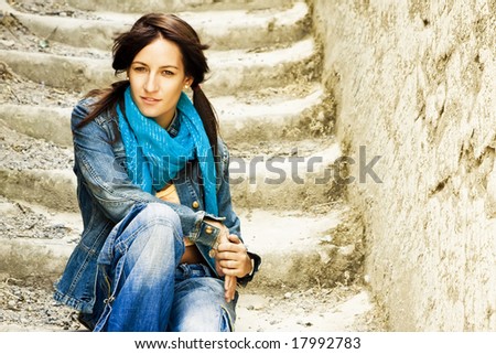 Young staring woman sitting on stone stairs.