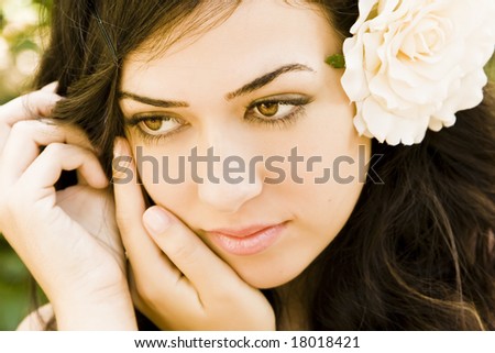 Young beautiful woman with a white rose in her hair.