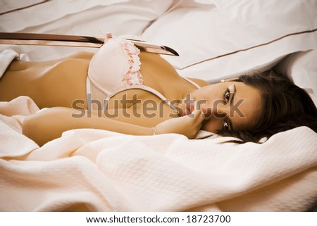 Young woman laying in bed in violent sexual scene.
