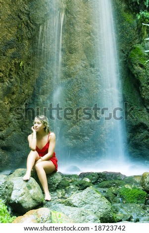Blond young pensive woman under long exposed waterfall
