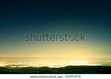 Stars raining over city at night. Long exposed picture.