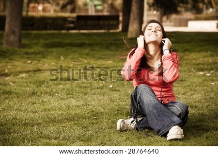 Young beauty listening music on the grass