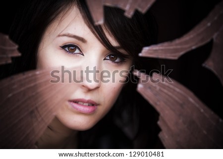 Woman looking through dirty broken glass