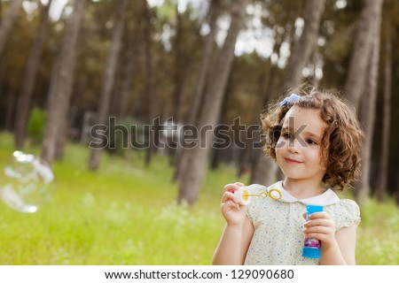 Portrait of funny lovely little girl making soap bubbles. Free space for your own bubbles.