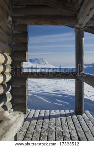 A wintery landscape seen through a cabin porch