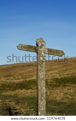 Footpath sign against hill and sky