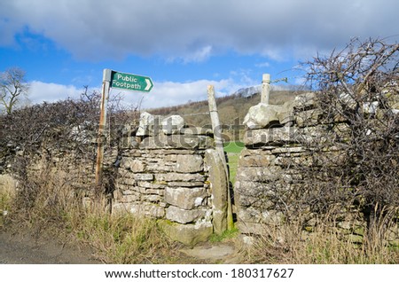 Metal footpath sign and style in dry stone wall
