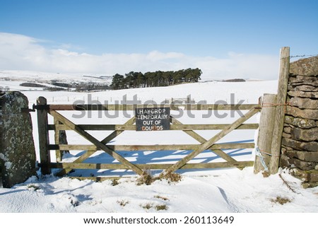 \'Hay crop temporary out of bounds\' sign on gate in the snow covered fields