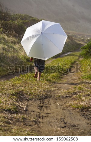 A small child using an umbrella for sun protection down at the beach. Location New Zealand, Kaikoura