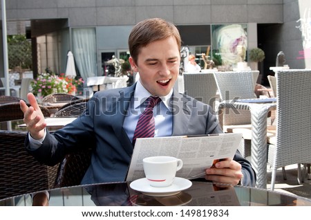 businessman emotionally reacts to the news in the newspaper