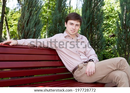 a young man sitting on a bench waiting for someone