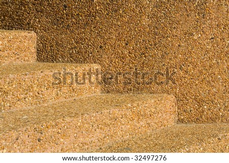 The abstract geometrical background formed by straight lines of a concrete ladder and a wall, ornated with a small color pebbles