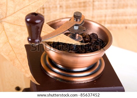 Coffee grinder and some scattered on the surface of a table of roasted coffee beans