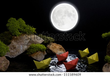 The composition of the stones, moss and paper boats, depicting sailing across the night sea between cliffs. The concept of a fragile dream world.
