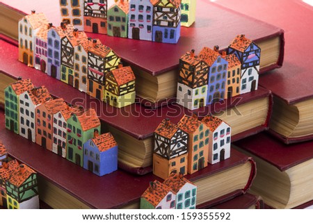 The painted wooden models of typical  buildings of European cities on a small scale with books on a white background. The concept of European culture traditions