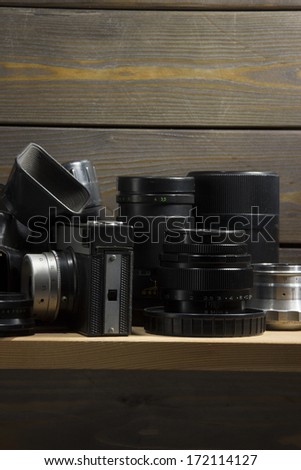 Wooden shelf in the larder with the old photographic equipment - lenses and cameras - outdated but still applicable.