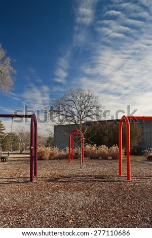 Three swing sets (one purple, one red, one orange) at St. Louis Forest Park on a sunny winter day with a few altocumulus clouds.