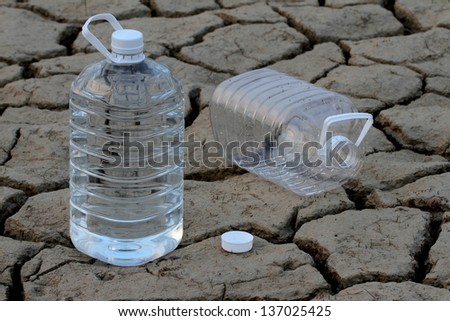 full and empty water bottle on Drought cracked earth