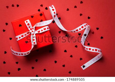Gift box with ribbon on red paper background. Valentines Day . Top view