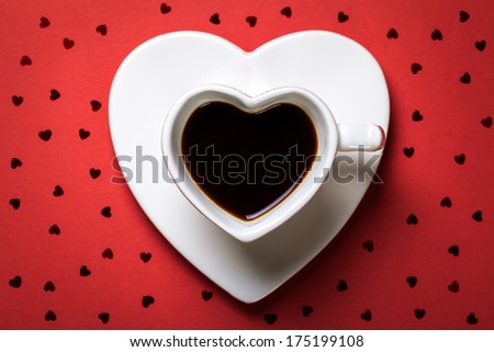 Coffee cup in shape of heart on red paper background. Top view