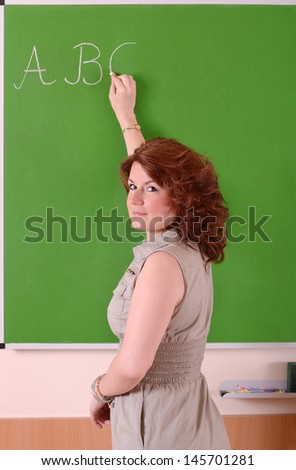 Teacher writing alphabet on a board in the school