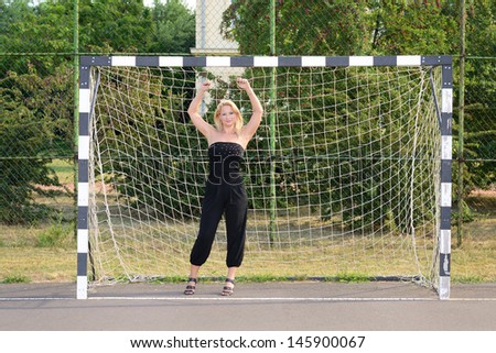 Beautiful blonde woman posing in the soccer goal
