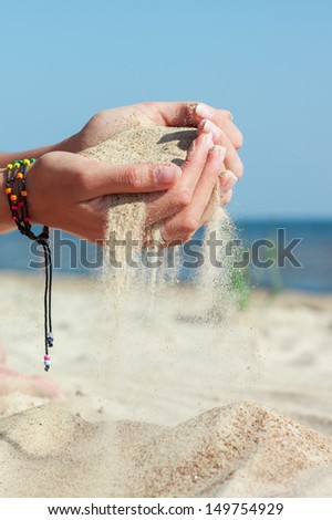 Woman pouring white sand with her hands on beach