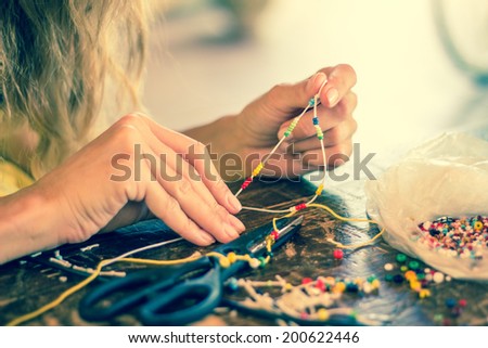 Woman making beaded bracelet with her hands, closeup