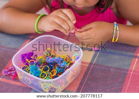 Little girl making bracelet with colorful rubber bands