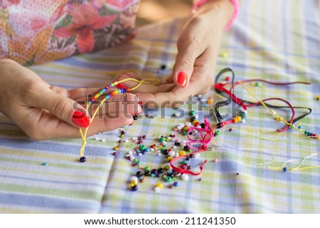 Woman making beaded bracelet with her hands