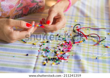 Woman making beaded bracelet with her hands
