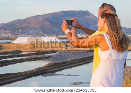 Tourists taking photo of salt at salt marsh at Nubia Sicily
