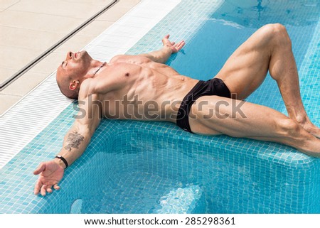 Handsome muscular man relaxing in swimming pool outdoors on summer day.