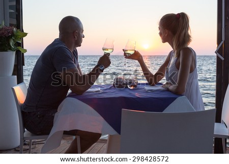 Couple dining in sea restaurant at sunset