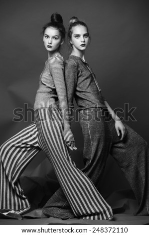 fashion portrait of two pretty model dance in studio on grey background
