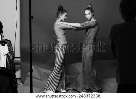 fashion portrait of two pretty model pose in studio on grey background