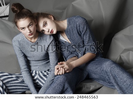 Two fashion models pose on gray background