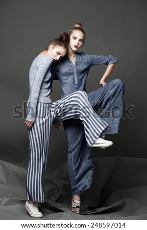 Two fashion models dance on gray background