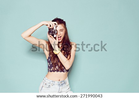 hipster photographer fashion stylish woman making photo using retro camera. Portrait on blue background