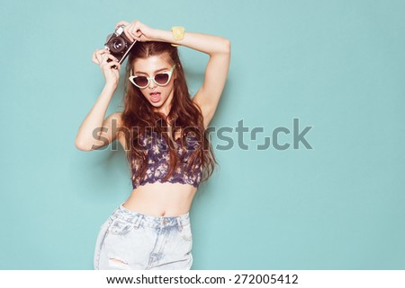 hipster photographer fashion stylish woman dancing and making photo using retro camera. Portrait on blue background