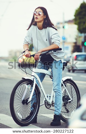 beautiful young hipster woman with bike in the city. Urban fashion lifestyle