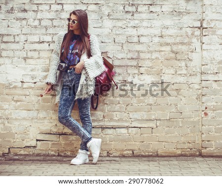 Young fashion woman flirting on the background of old brick wall. Outdoors, lifestyle.