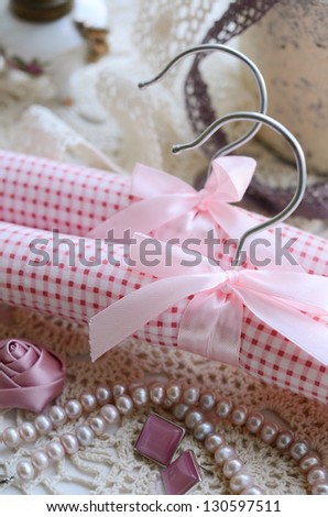 Decoration with pink clothing hangers with ribbon and bow on crocheted background in vintage style