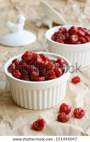 White bowl full of sweet dried cherries on paper background