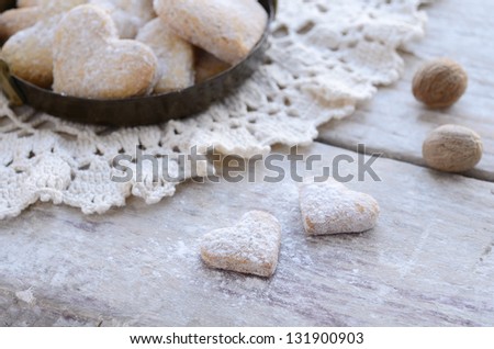 Homemade heart shaped biscuits powdered with sugar on wooden background in French style