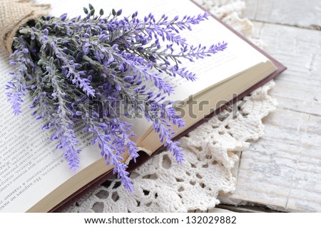 Decoration in French style - bunch of lavender laying upon open book on vintage crocheted doily