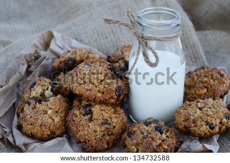 Homemade oatmeal cookies with nuts and raisins and bottle of milk on canvas background