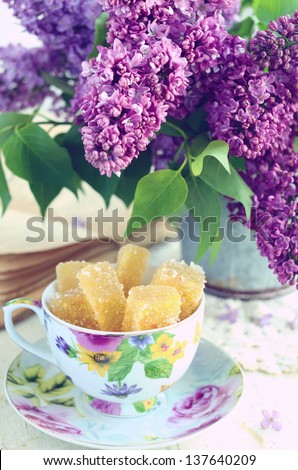 Cup with homemade marmalade bars, lilac flowers in old metal bucket and vintage book - still life
