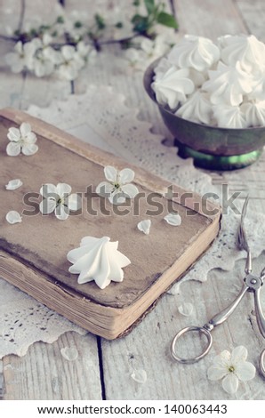 Still life in vintage style with meringue kisses and cherry flowers on rusted wooden table
